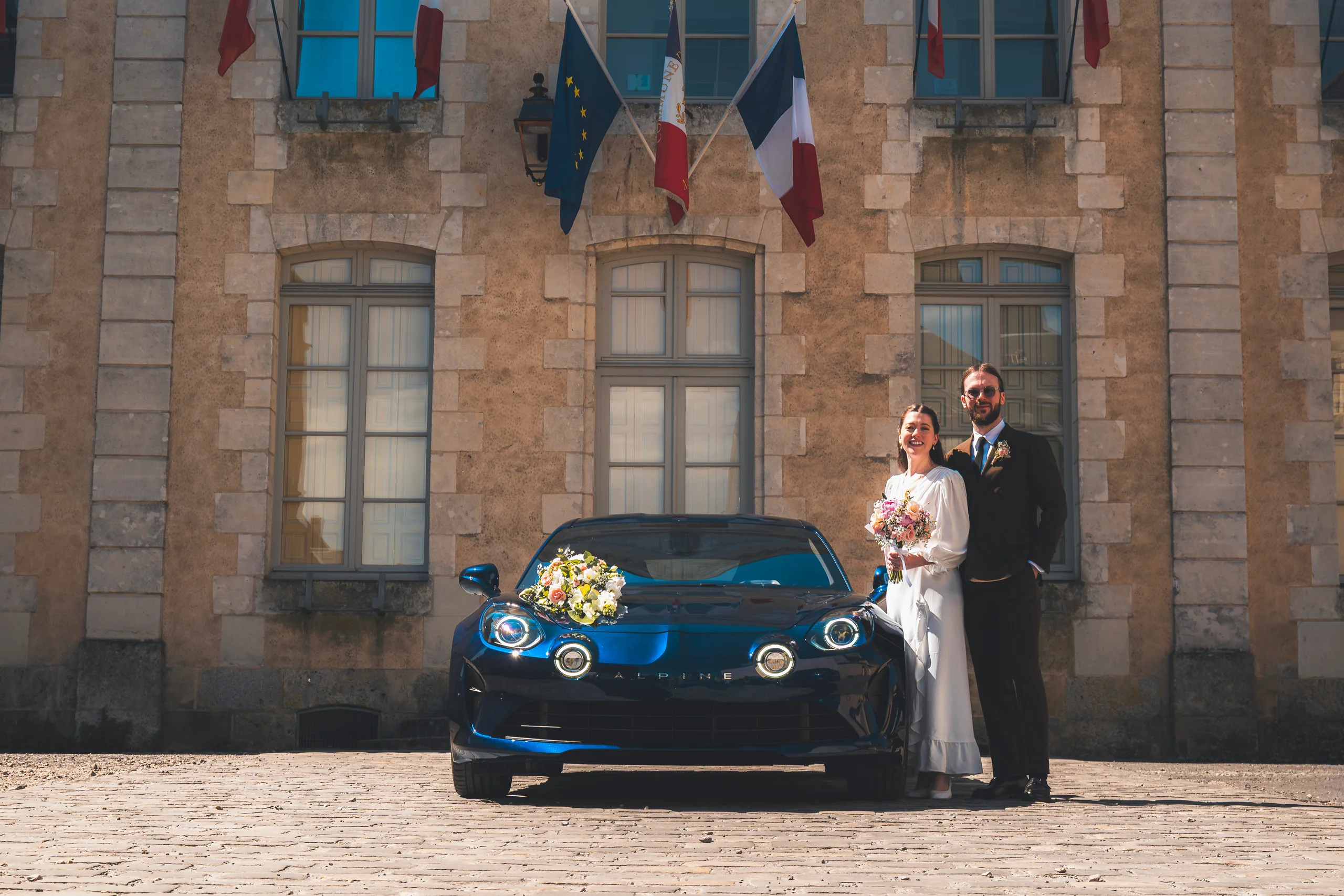 Morgane et Nicolas devant la mairie avec une Alpine
